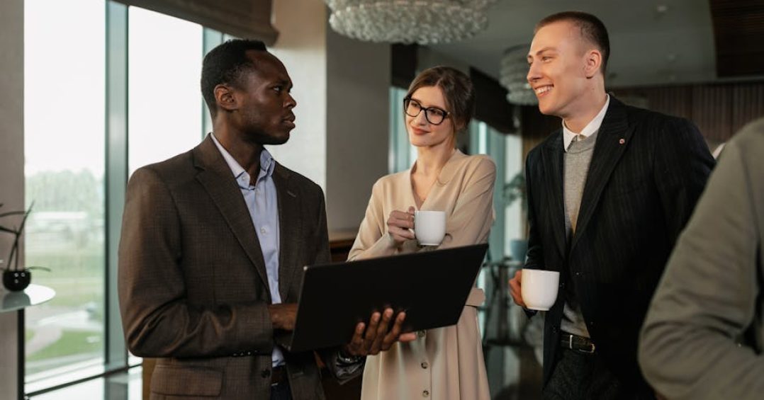 Man in Brown Business Suit Holding Black Laptop while Standing